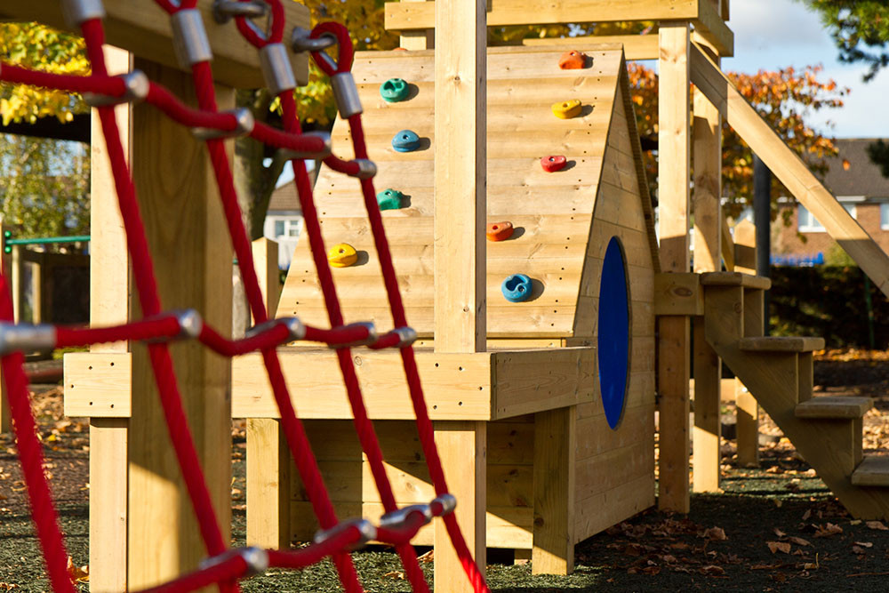 Playground apparatus with wooden climbing wall and climbing netting