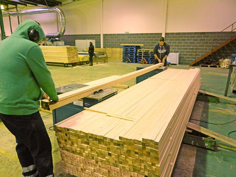 Two workers packing sawn timbers together