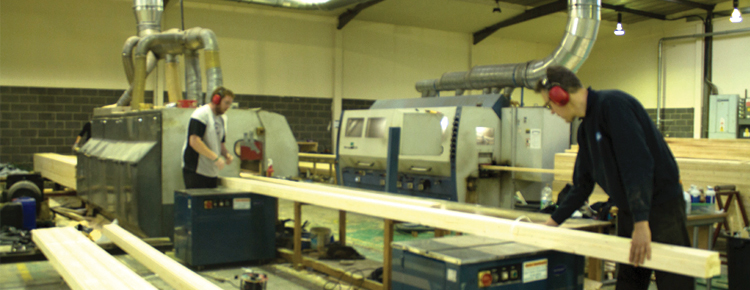 Inside the workshop with a worker working on some planed timbers